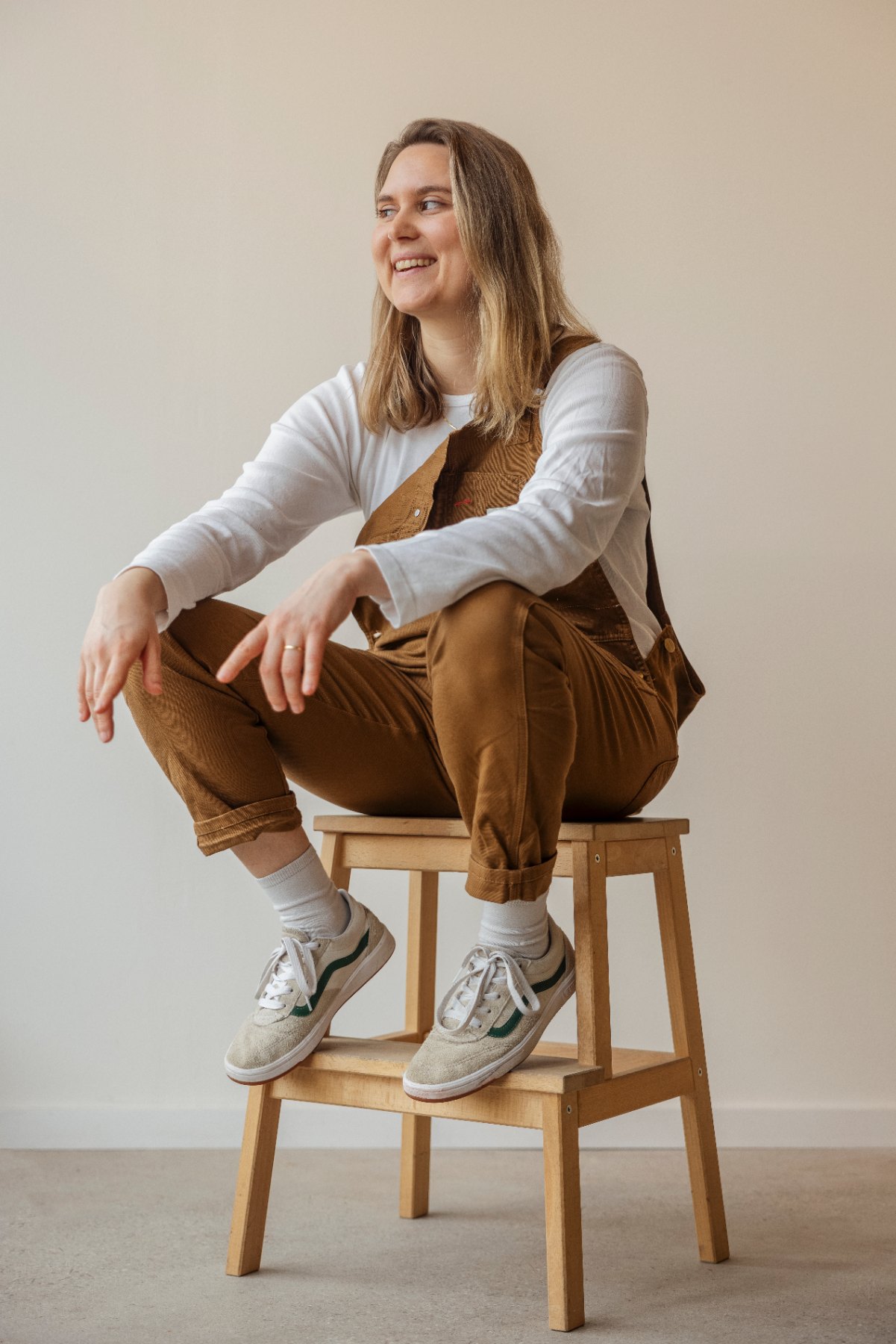 Frau DJ sitzt lachend auf einem Holzhocker
